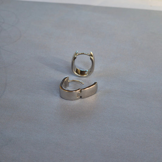Sorellla of May sterling silver huggie earrings sitting on plain backgraoun