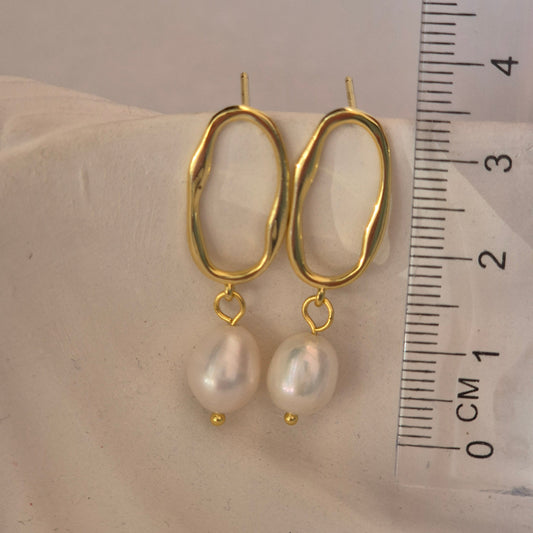 Sorella of May Alba pearl and gold drop earring beside a ruler