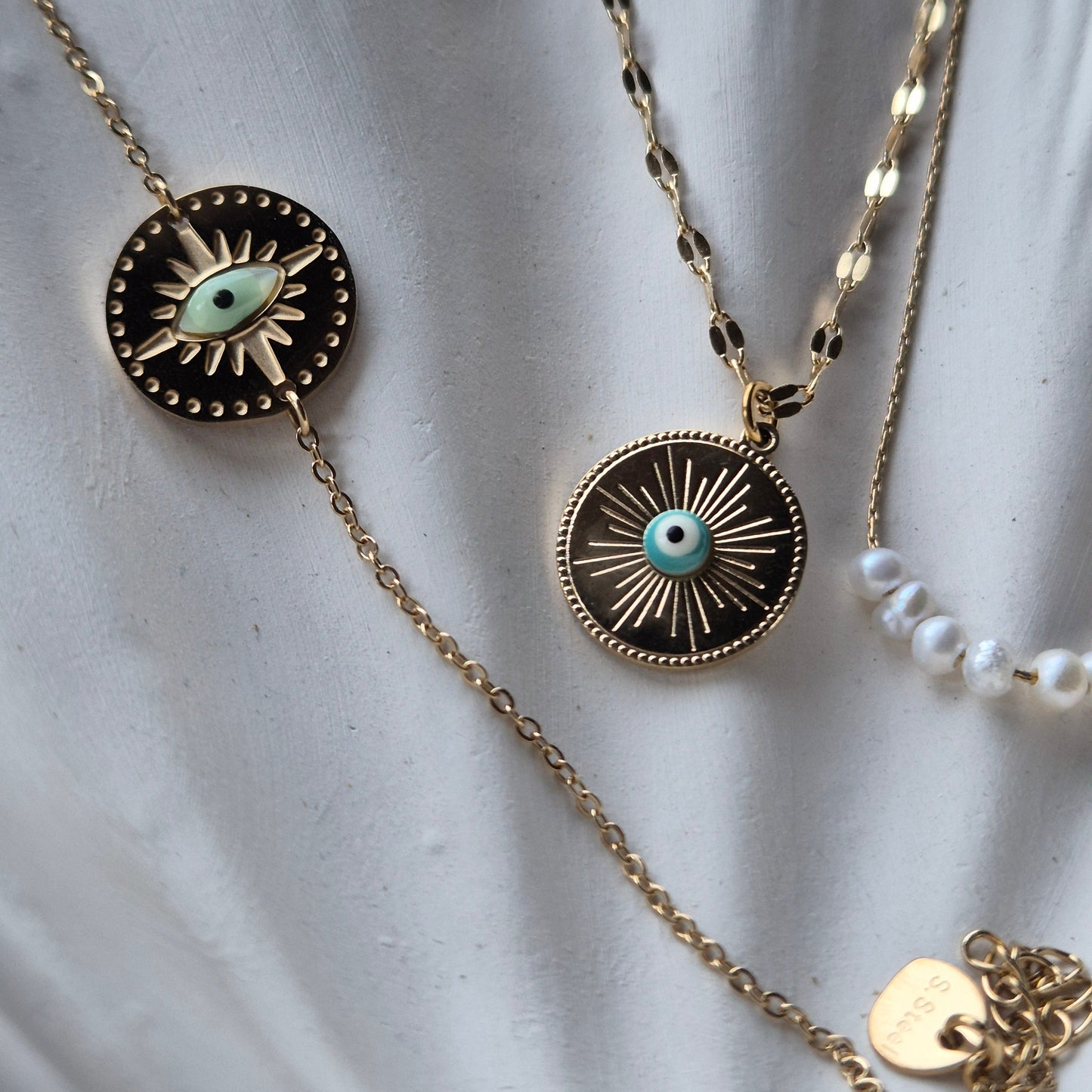 Sorella of May Gold Bracelet and Necklace with Evil Eye pendants on cream coloured background