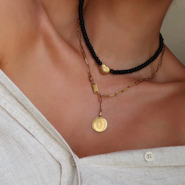 Close up shot of person wearing the  Maira Black bead necklace and the Madusa paperchain necklace