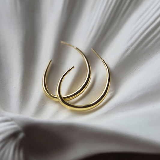 Gold hoop earrings on a white fabric background