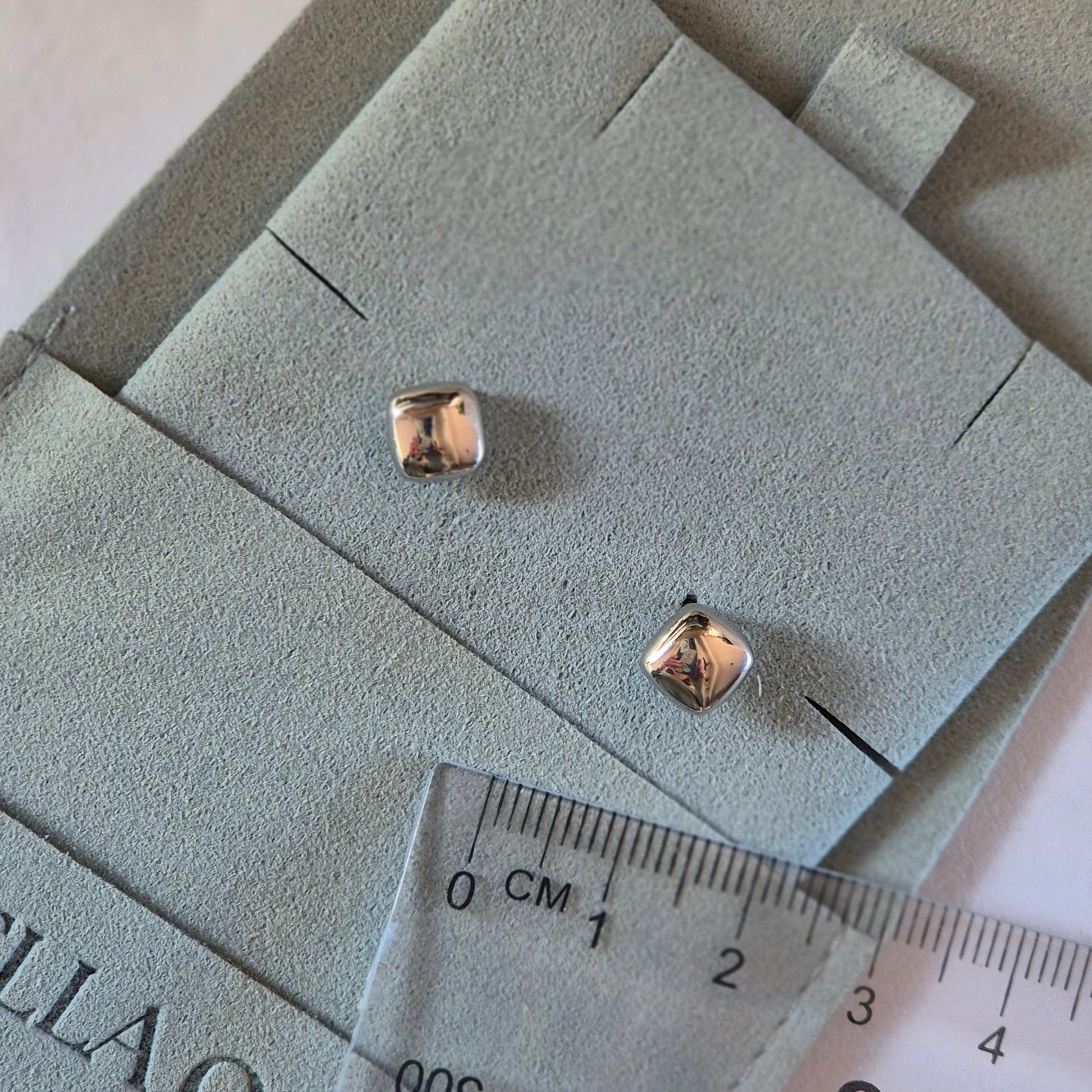 Stering silver square shape studs next to a ruler for size. Studs 5mm wide. In Sterling Silver.