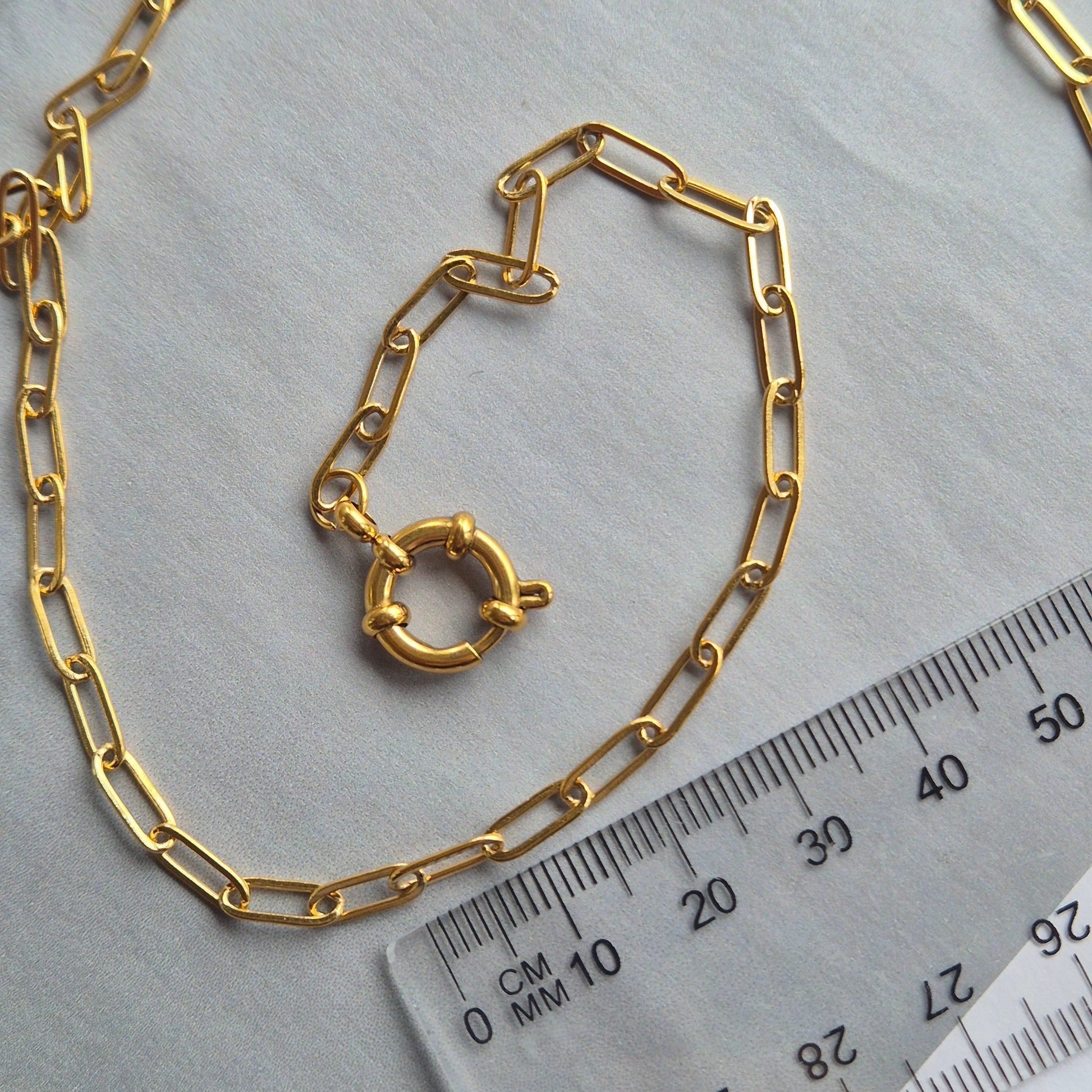 Sorella of May Noa paperclip gold necklace besides a ruler