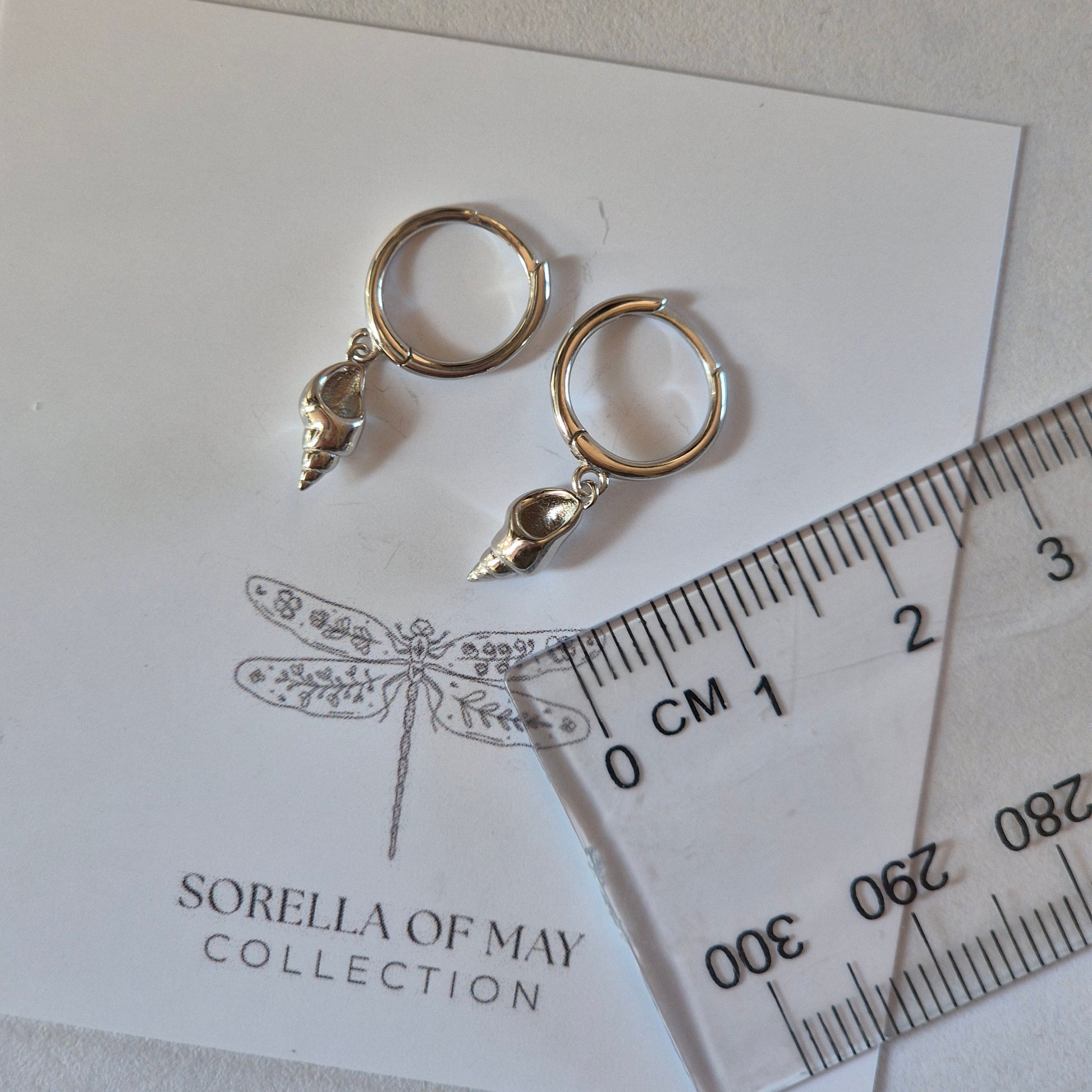 Sorella of May Ocean Shell earring beside a ruler