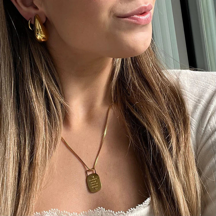 Close-up of a person wearing a gold necklace and earrings.
