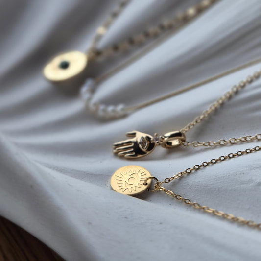 Sorella of May Hamsa hand necklace on dish with other necklaces