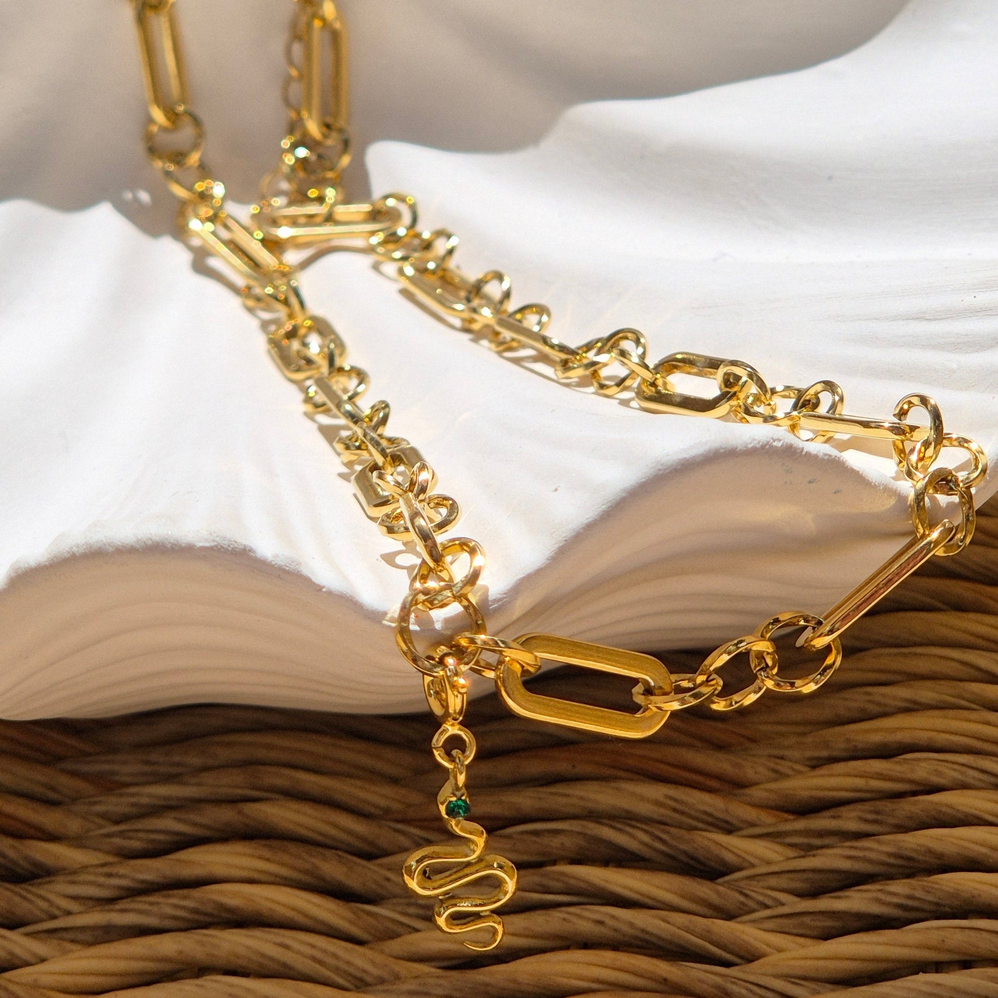 Shay gold chain necklace with detachable snake charm resting on dish