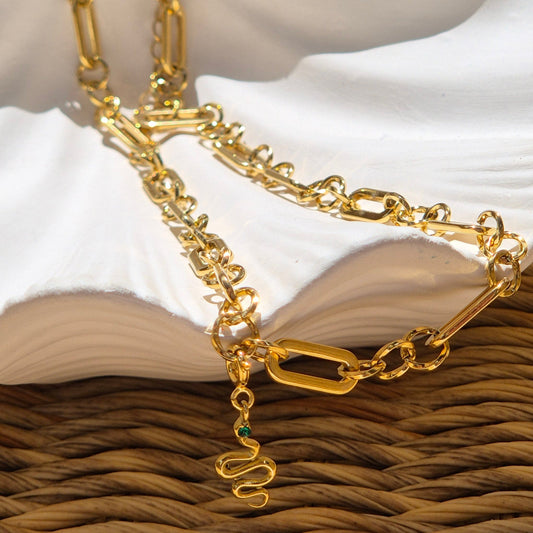 Shay gold chain necklace with detachable snake charm resting on dish
